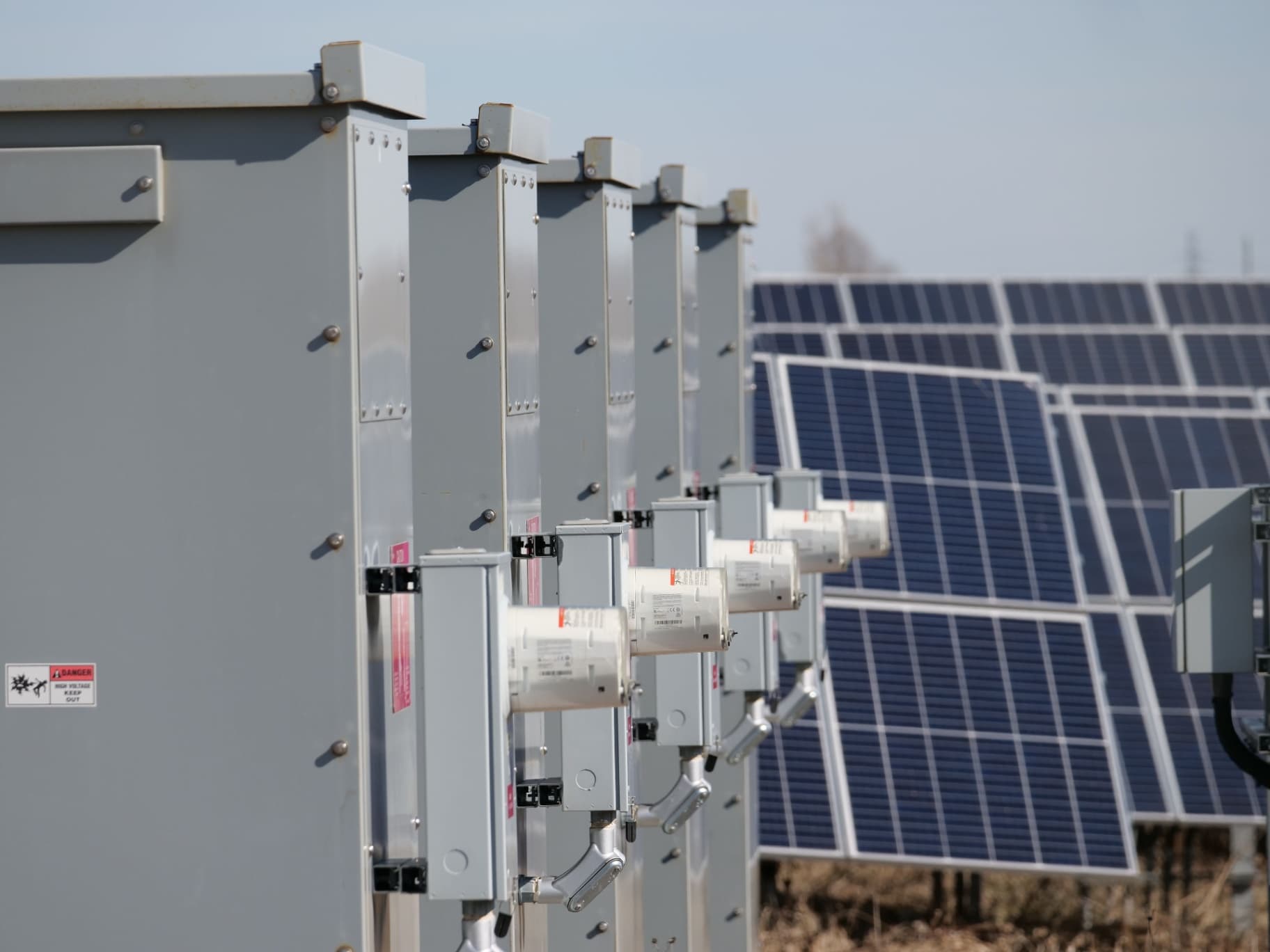 Séria vonkajších elektrických rozvádzačov pri radoch solárnych panelov v teréne