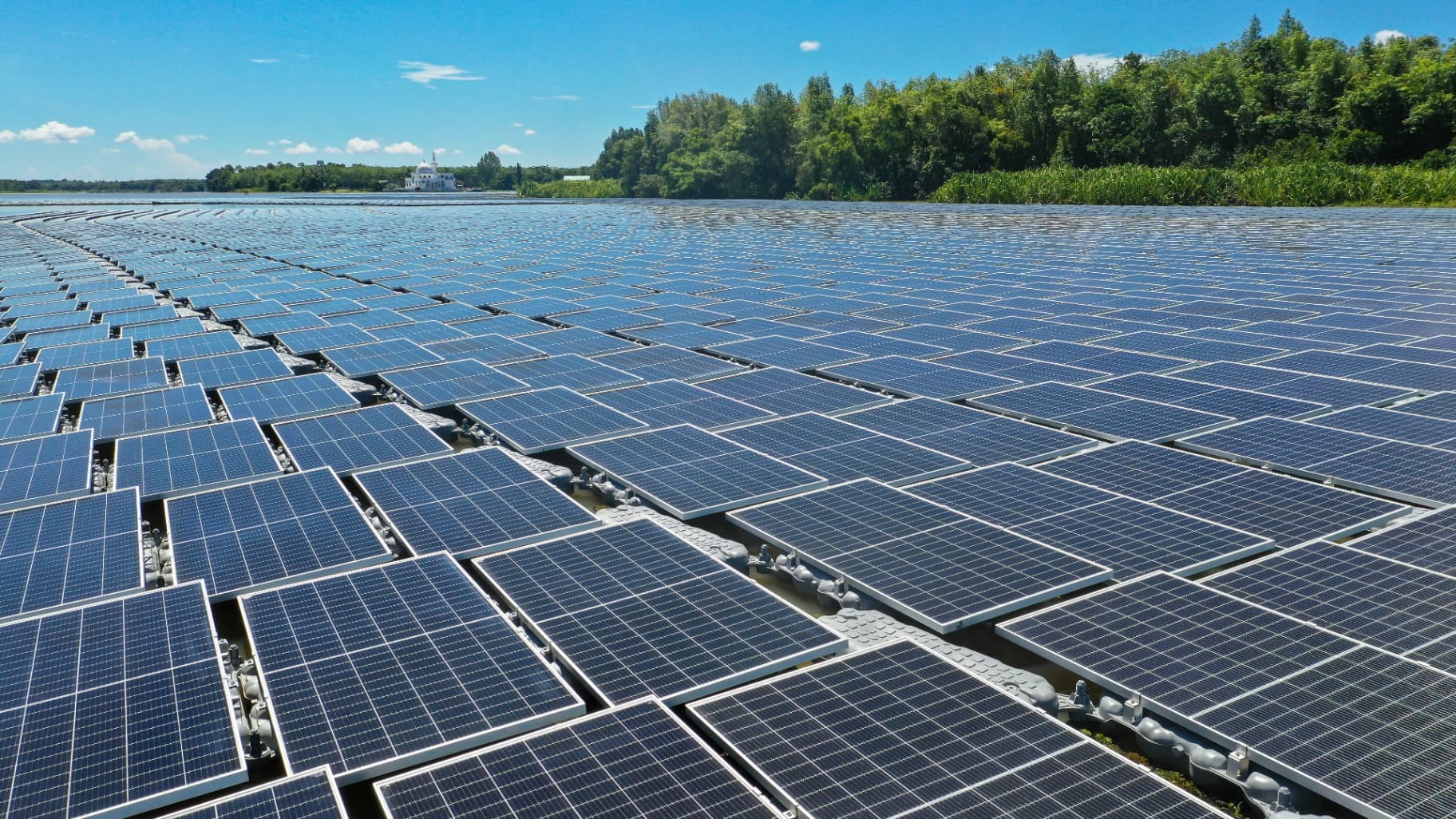 Pohľad na plávajúcu solárnu elektráreň na vodnej hladine s lesom v pozadí